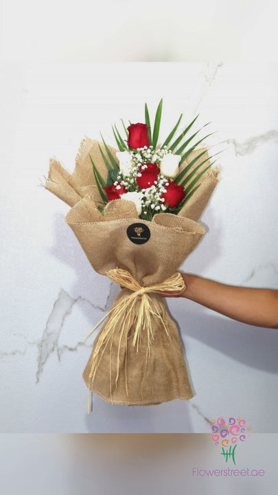 Red and white roses with baby's breath in natural jute wrapping