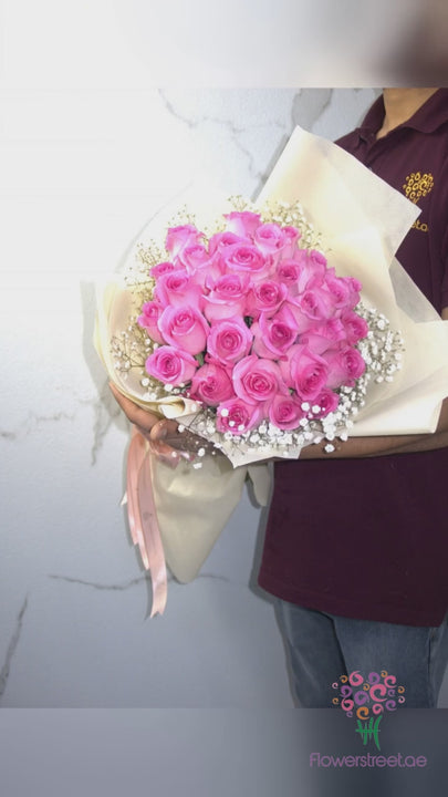Twenty-four pink roses with baby's breath in cream wrapping