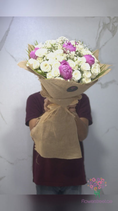 Pink and purple blooms with white spray roses in jute wrapping