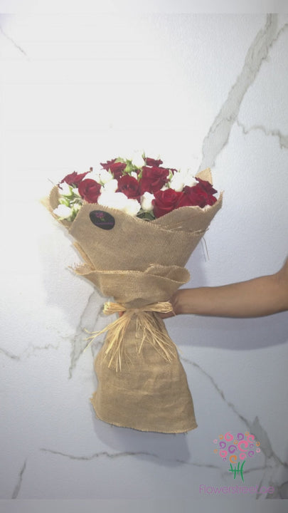Red roses and white spray roses in natural jute wrapping