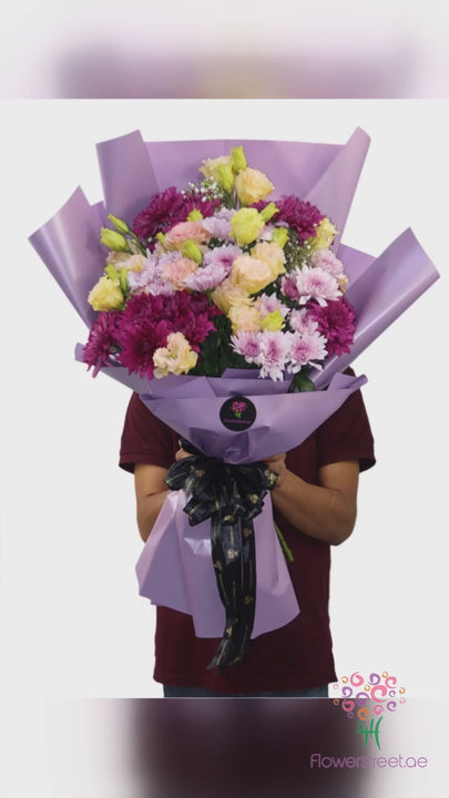 Purple and lilac mixed flower bouquet in purple and white wrapping