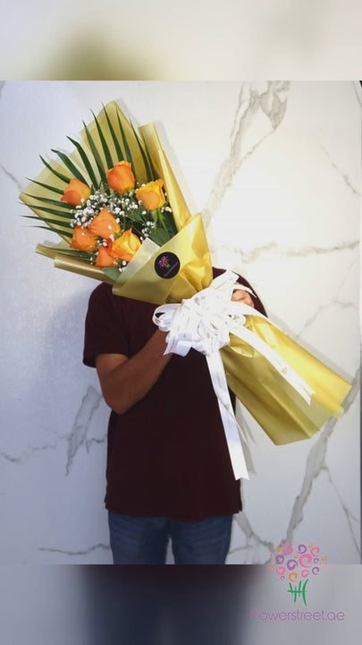 Seven orange roses with baby's breath in gold wrapping