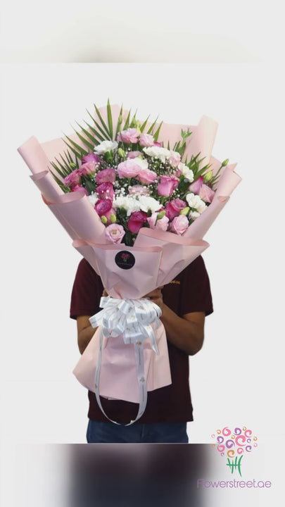Pink roses, carnations and white blooms in pale pink wrapping