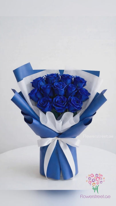 Royal blue rose bouquet in blue and white wrapping, filmed in warm light as petals fall past