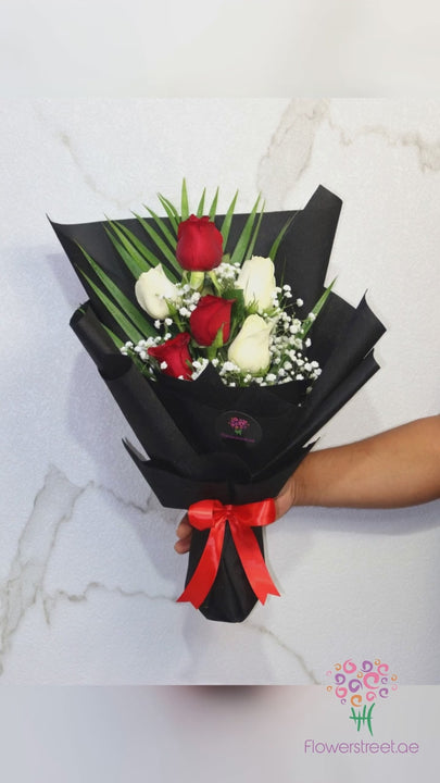 Six red and white roses with baby's breath in black wrapping