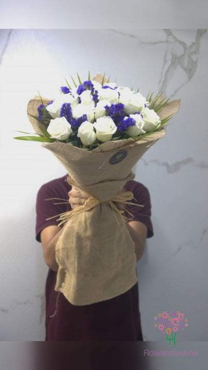 Twenty white roses with purple statice in natural jute wrapping