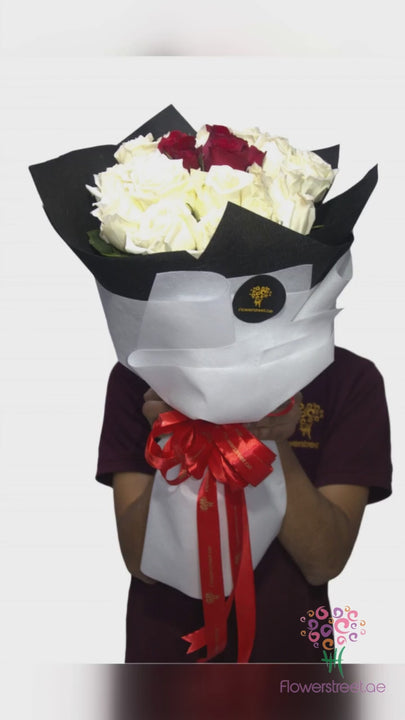 White roses with deep red roses in the centre, black and white wrapping