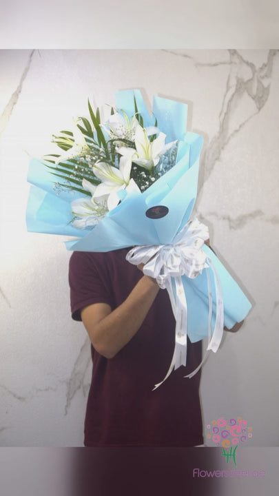 White lilies with green foliage in light blue wrapping