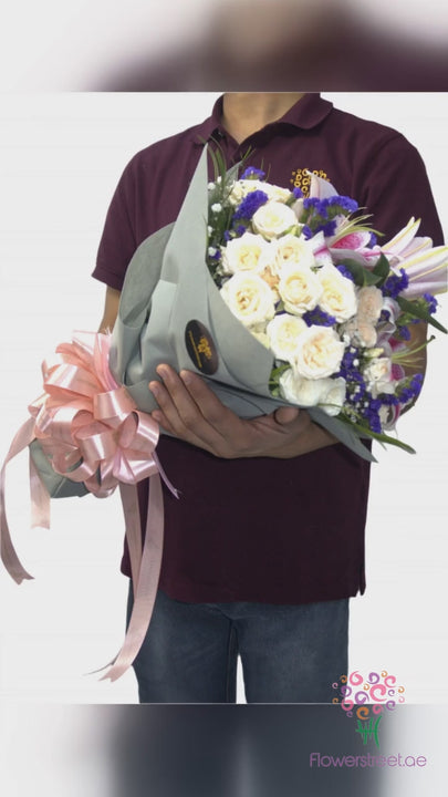 Cream and peach roses with blue and purple blooms in sage green wrapping
