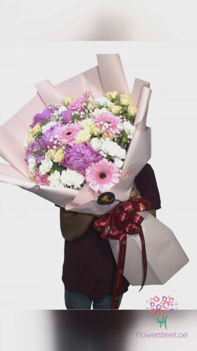 Mixed bouquet of lilac gerberas and cream blooms in pale pink wrapping