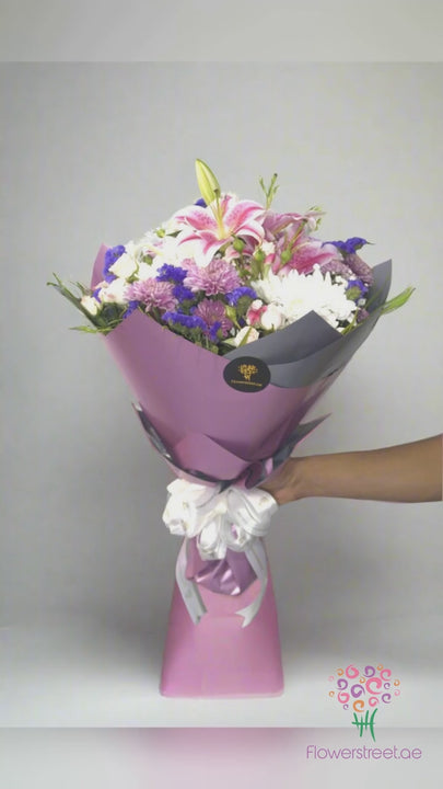 Pink lilies with blue and purple statice in pink wrapping