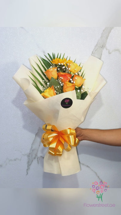 Orange and yellow roses with palm leaves in cream wrapping