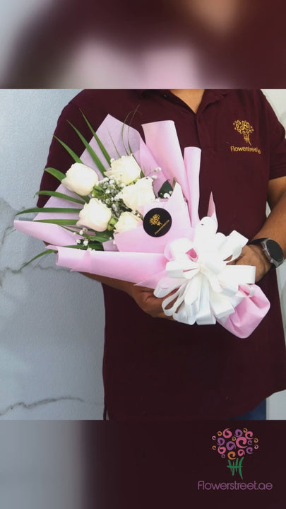 Small bouquet of white roses in pale pink wrapping