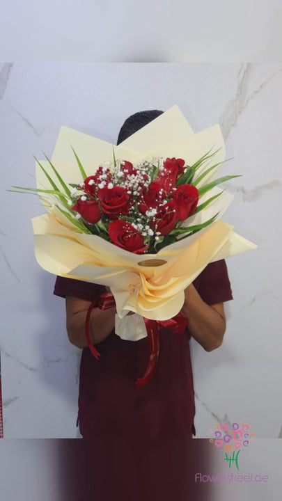 Twelve red roses with baby's breath in cream wrapping